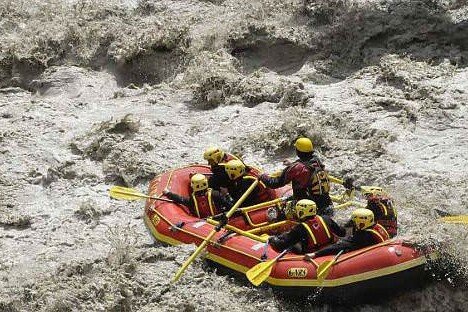 Totem Advenuture A group of people on board an inflatable boat navigate through rough and muddy waters, experiencing exciting outdoor experiences in the Aosta Valley. Rafting Kayaking Paragliding Canyoning Aosta Valley