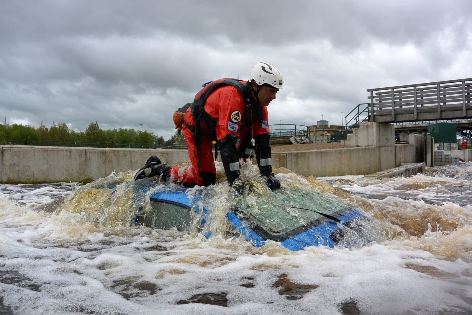 Totem Advenuture Amidst the turbulent flood waters under cloudy skies, a rescuer in a red suit braves the elements on the roof of a submerged car. Reminiscent of the thrills of rafting in the Aosta Valley, where adventure meets resilience. Rafting Kayaking Paragliding Canyoning Aosta Valley