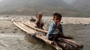 Totem Advenuture Due bambini sono seduti su una zattera di bambù lungo la riva di un fiume, con le mani giunte in segno di saluto. Questo momento di tranquillità fa presagire che questo sarà l'anno dell'amicizia e dei nuovi inizi. Rafting Kayaking Parapendio Canyoning Valle d’Aosta