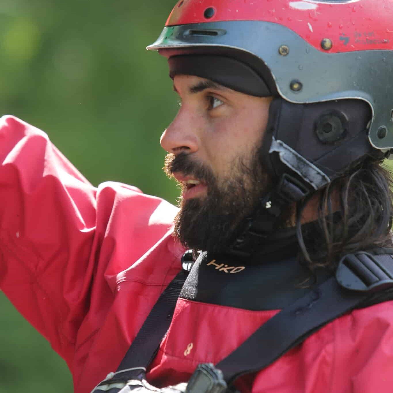 Totem Adventure A bearded man wearing a helmet and a red jacket, possibly kayaking with Team Totem Adventure, raises his arm in the open. Rafting Kayaking Paragliding Canyoning Aosta Valley