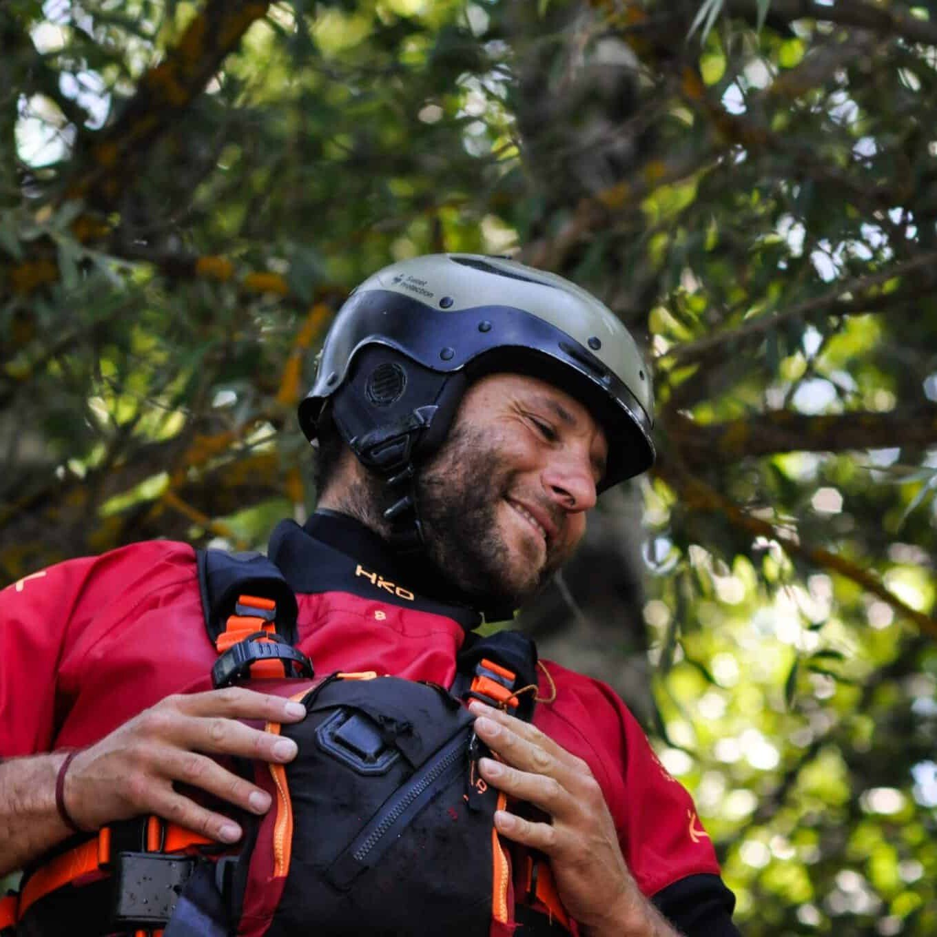 Totem Advenuture A man in a red shirt and helmet smiles outdoors, surrounded by leafy trees, ready for an adventure by Team Totem. Rafting Kayaking Paragliding Canyoning Aosta Valley