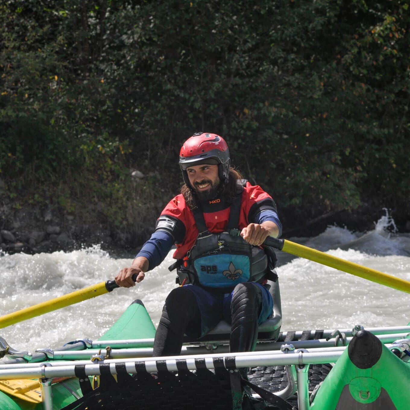 Totem Advenuture Una persona con casco e giubbotto di salvataggio conduce una zattera lungo un fiume in rapida evoluzione, abbracciando lo spirito dell'avventura del team totem. Rafting Kayaking Parapendio Canyoning Valle d’Aosta