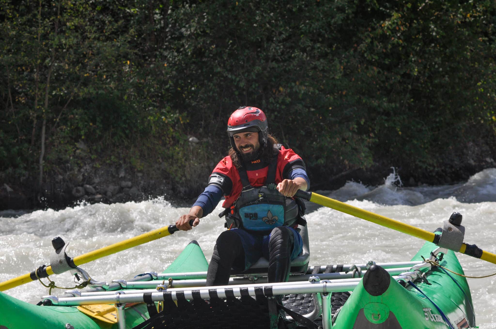 Totem Advenuture Una persona con casco e giubbotto di salvataggio conduce una zattera lungo un fiume in rapida evoluzione, abbracciando lo spirito dell'avventura del team totem. Rafting Kayaking Parapendio Canyoning Valle d’Aosta