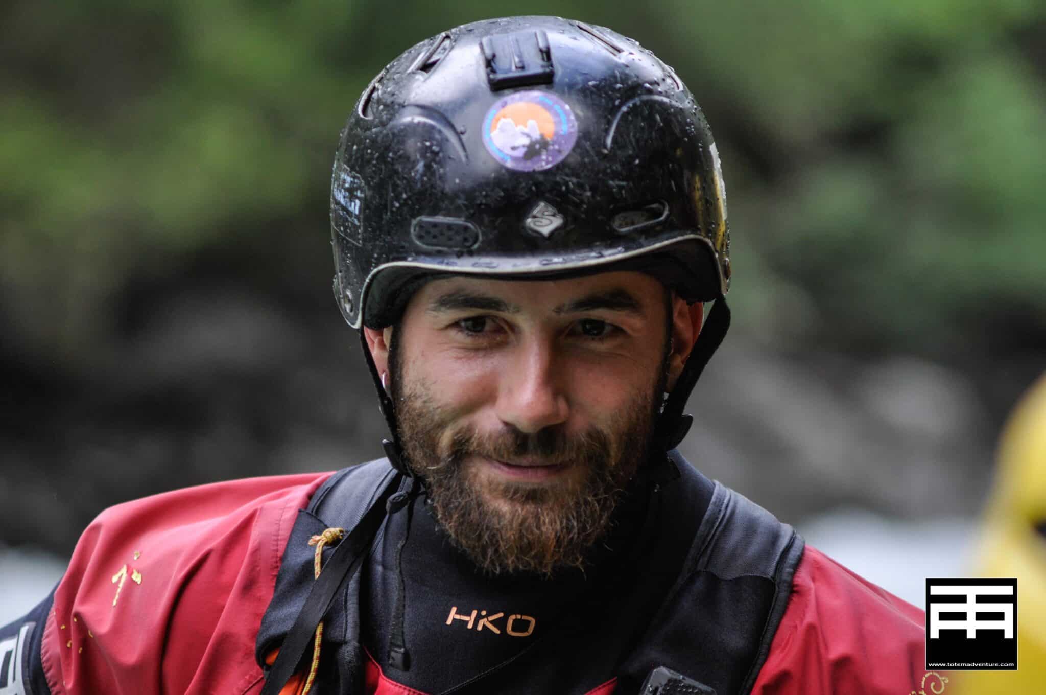 Totem Advenuture A man in a red jacket and black helmet smiles outdoors against a blurred natural background. Rafting Kayaking Paragliding Canyoning Aosta Valley
