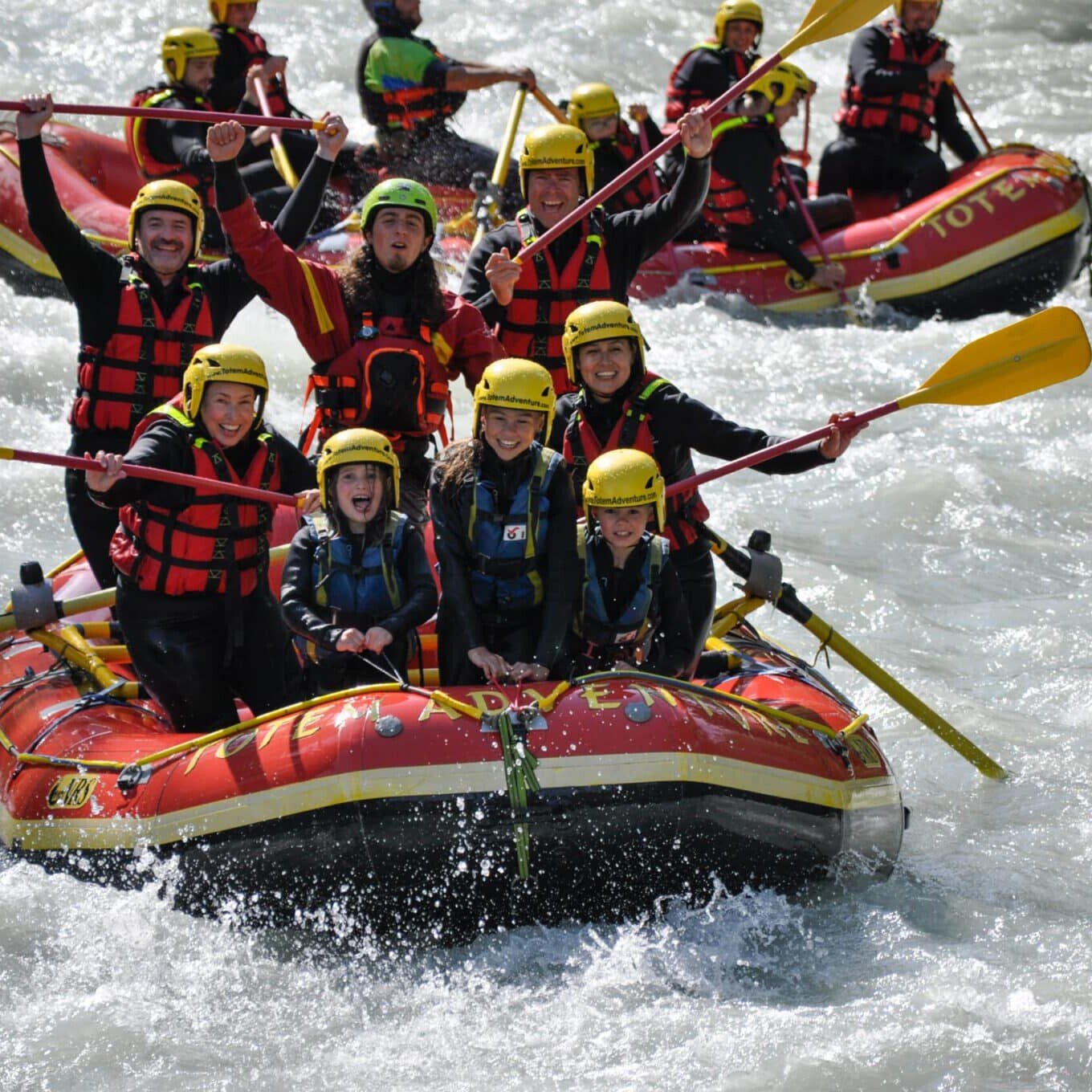 Totem Advenuture Gruppi di persone con caschi e giubbotti di salvataggio praticano rafting, alzando le pagaie e applaudendo nel cuore dell'avventura a Pré Saint Didier, dove le esperienze più intense definiscono il brivido dell'aria aperta. Rafting Kayaking Parapendio Canyoning Valle d’Aosta