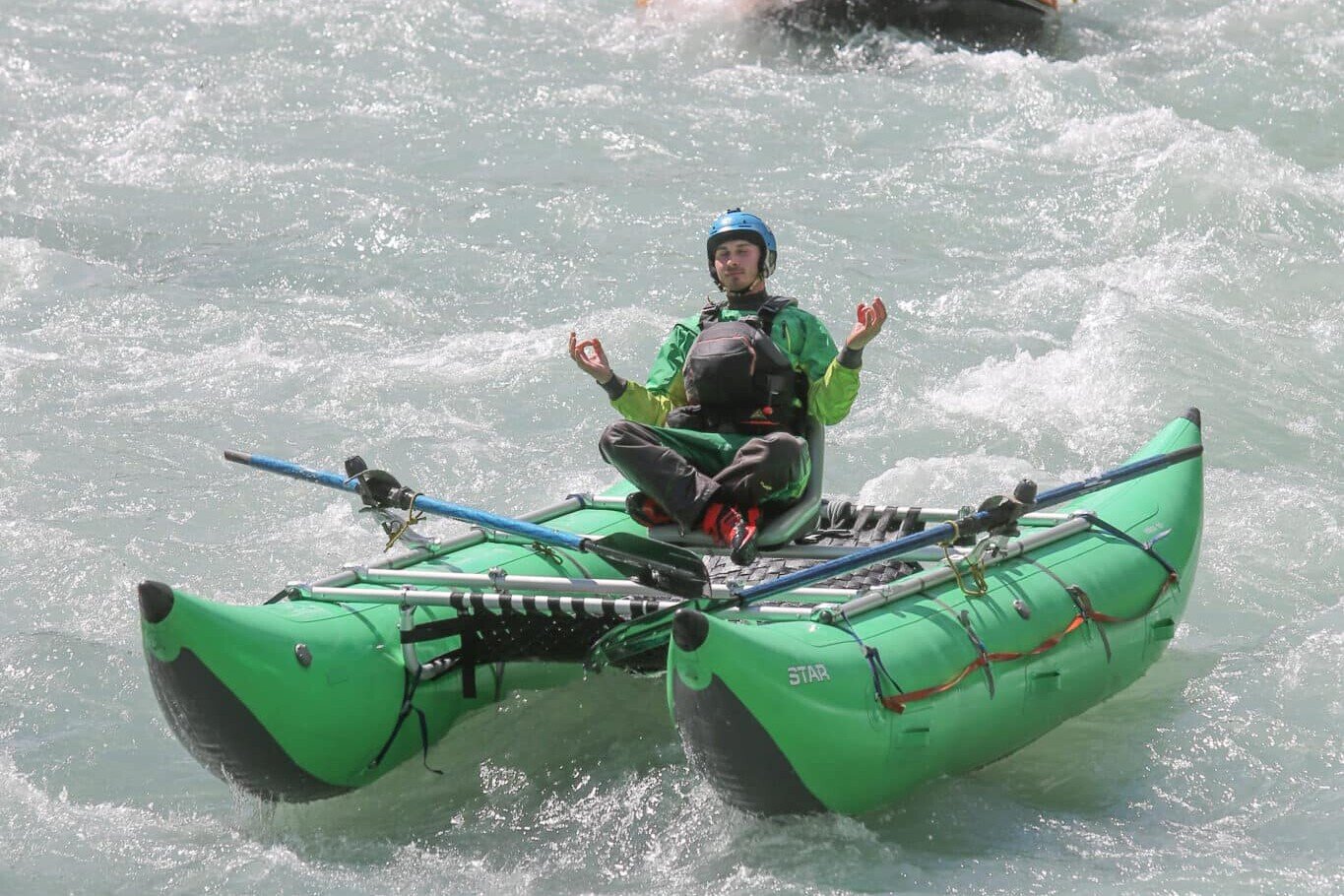 Totem Advenuture Una persona medita su una zattera verde, guidando con calma un gruppo di rafters lungo un fiume in rapida evoluzione, aiutandoli a superare la loro paura di rafting. Rafting Kayaking Parapendio Canyoning Valle d’Aosta