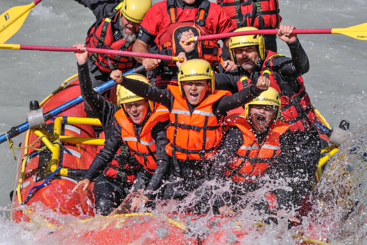 Famiglia con bambini durante un'esperienza di rafting sulla Dora Baltea in Valle d'Aosta con le guide di Totem Adventure, tra rapide, divertimento e massima sicurezza.
