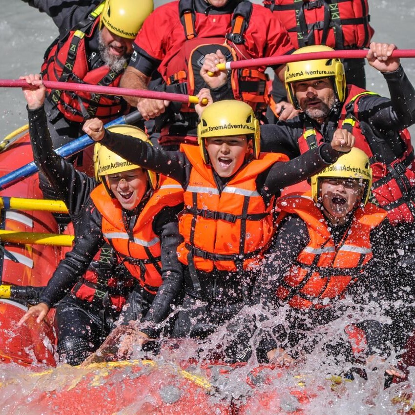 Famiglia con bambini durante un'esperienza di rafting sulla Dora Baltea in Valle d'Aosta con le guide di Totem Adventure, tra rapide, divertimento e massima sicurezza.